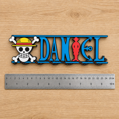 Personalized One Piece DANIEL nameplate displayed beside a dual-scale centimeter and inch ruler.